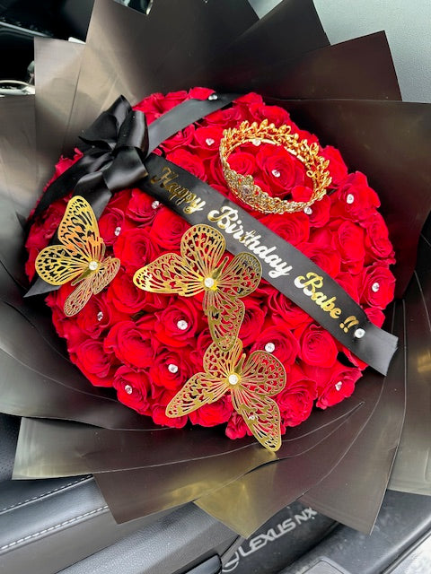 Red rose bouquet with black wrap, gold crown, and gold butterflies by Bianca's Flowers